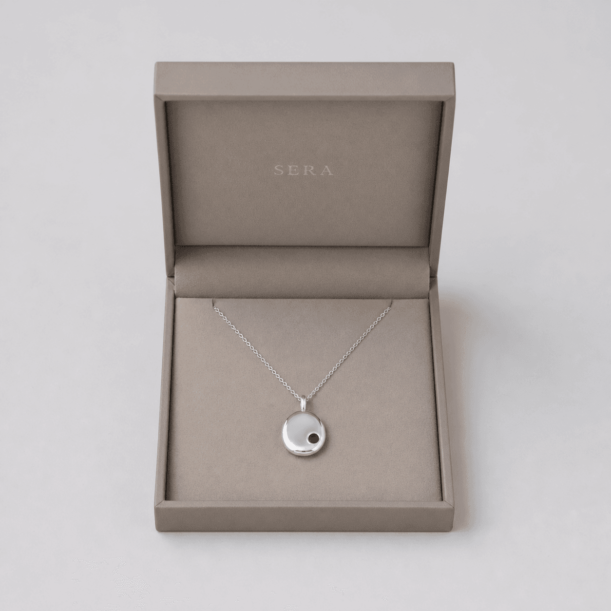 Demo source photo of a fictional SERA pendant necklace in a neutral jewelry box